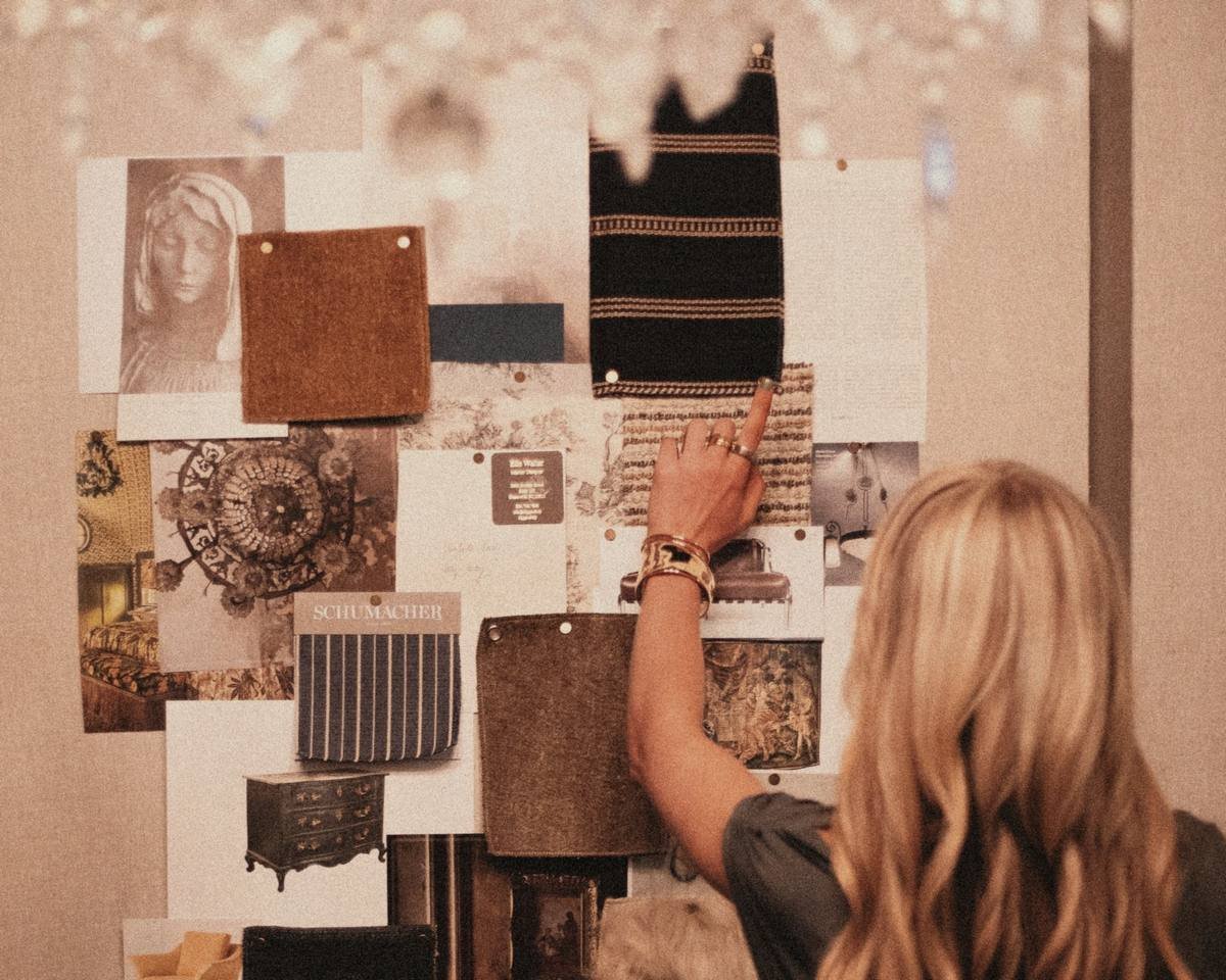 A designer pinning samples to a mood board in a warm, dim studio