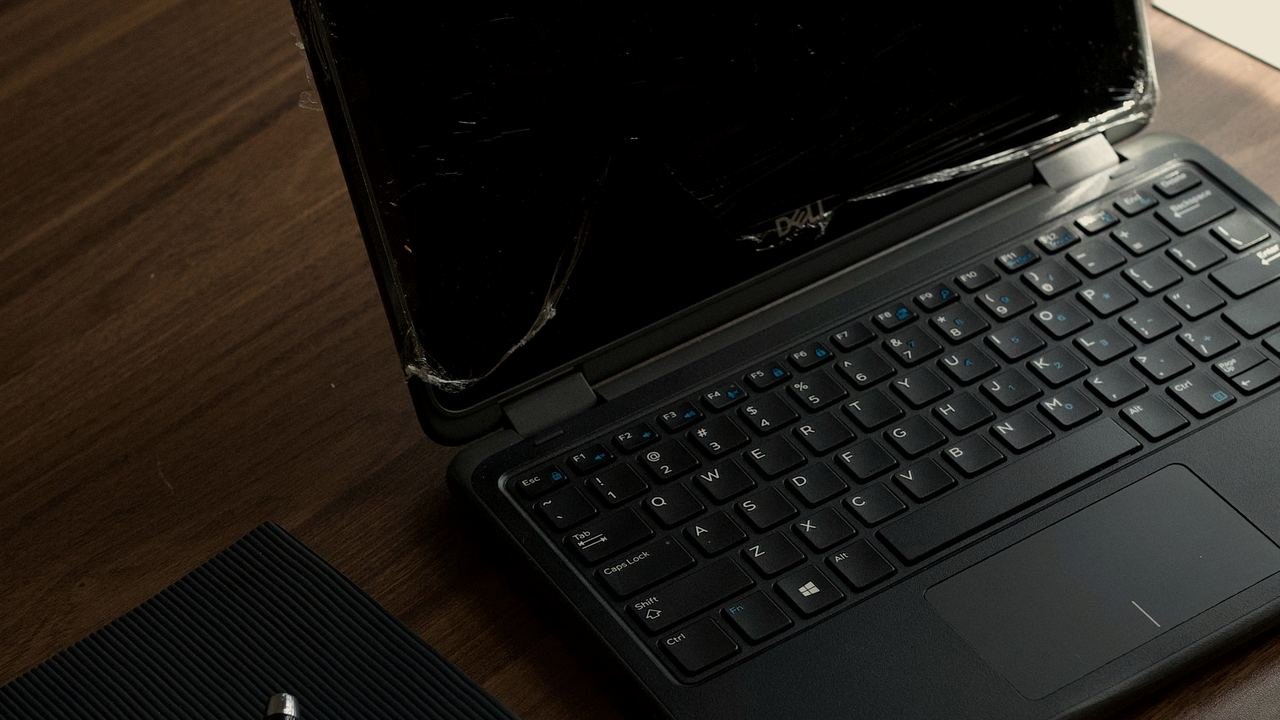 Una laptop y una libreta sobre un escritorio de madera oscuro